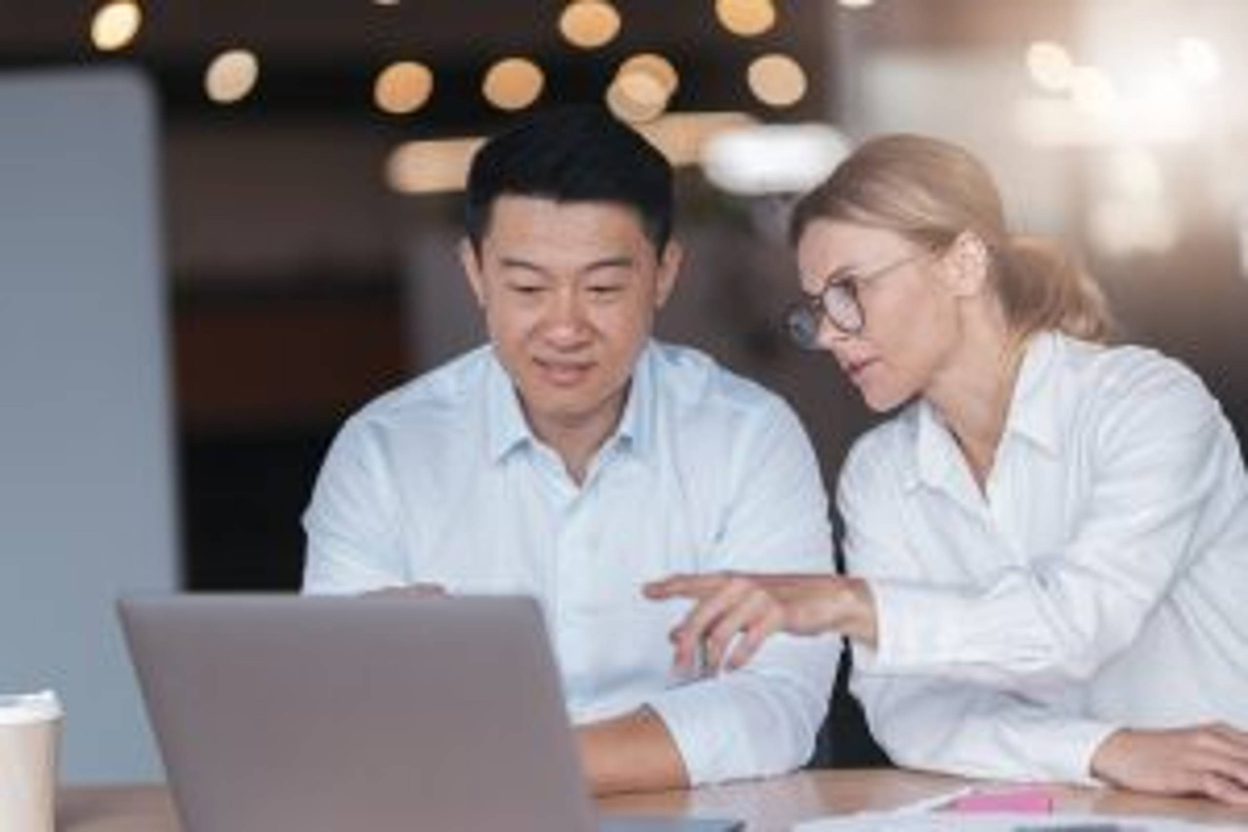 Two business people focused while working on a laptop together at boardroom table in office